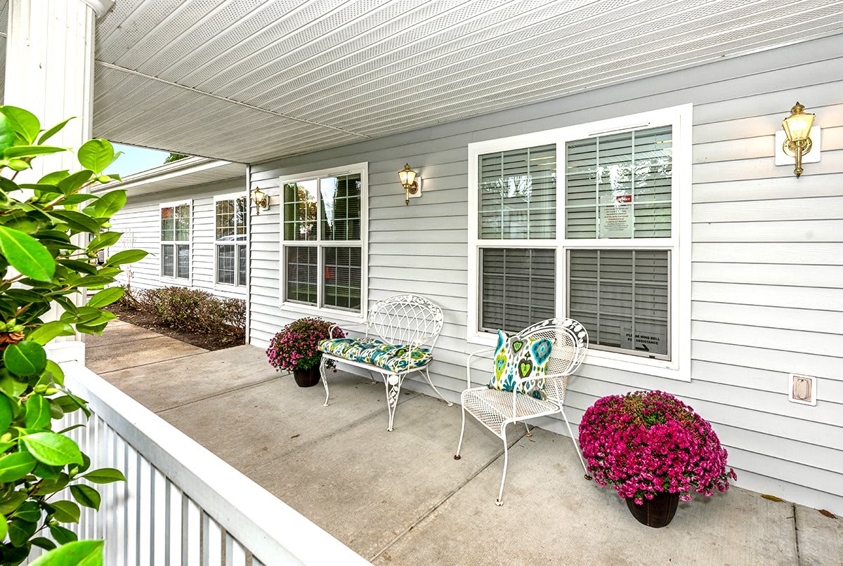 A cozy porch area with seating and colorful potted flowers.