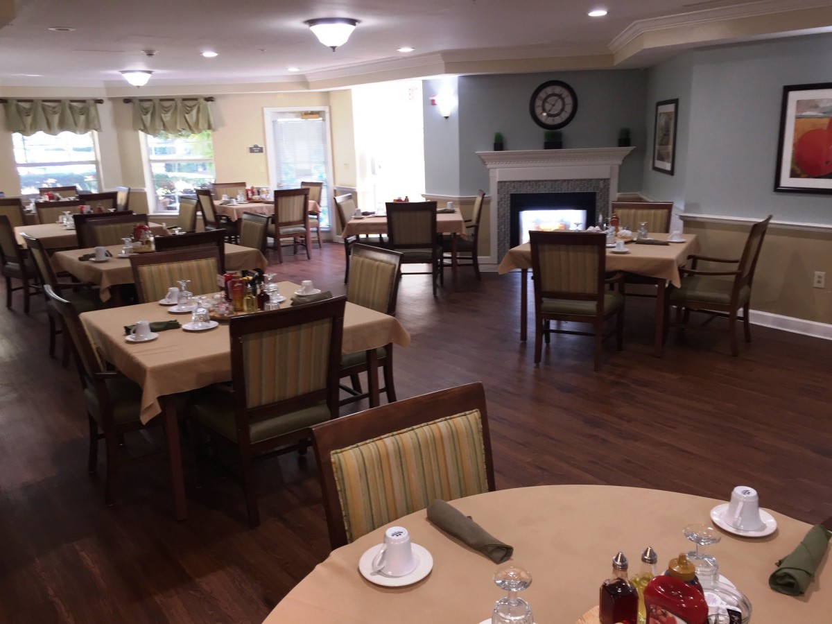 A neatly arranged dining room with several set tables and a fireplace.