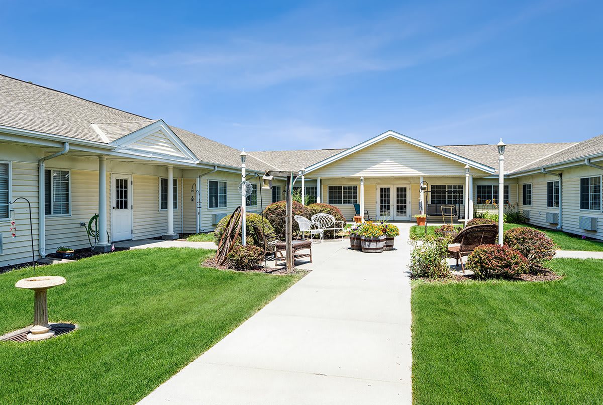 A sunny view of a residential building with well-maintained landscaping and a central walkway.