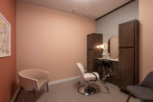 A cozy salon room with a styling chair and mirror setup.