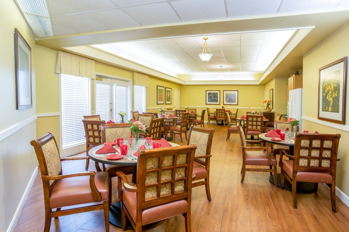 A well-lit dining area with neatly arranged tables and chairs, featuring wooden furniture and tasteful decor.