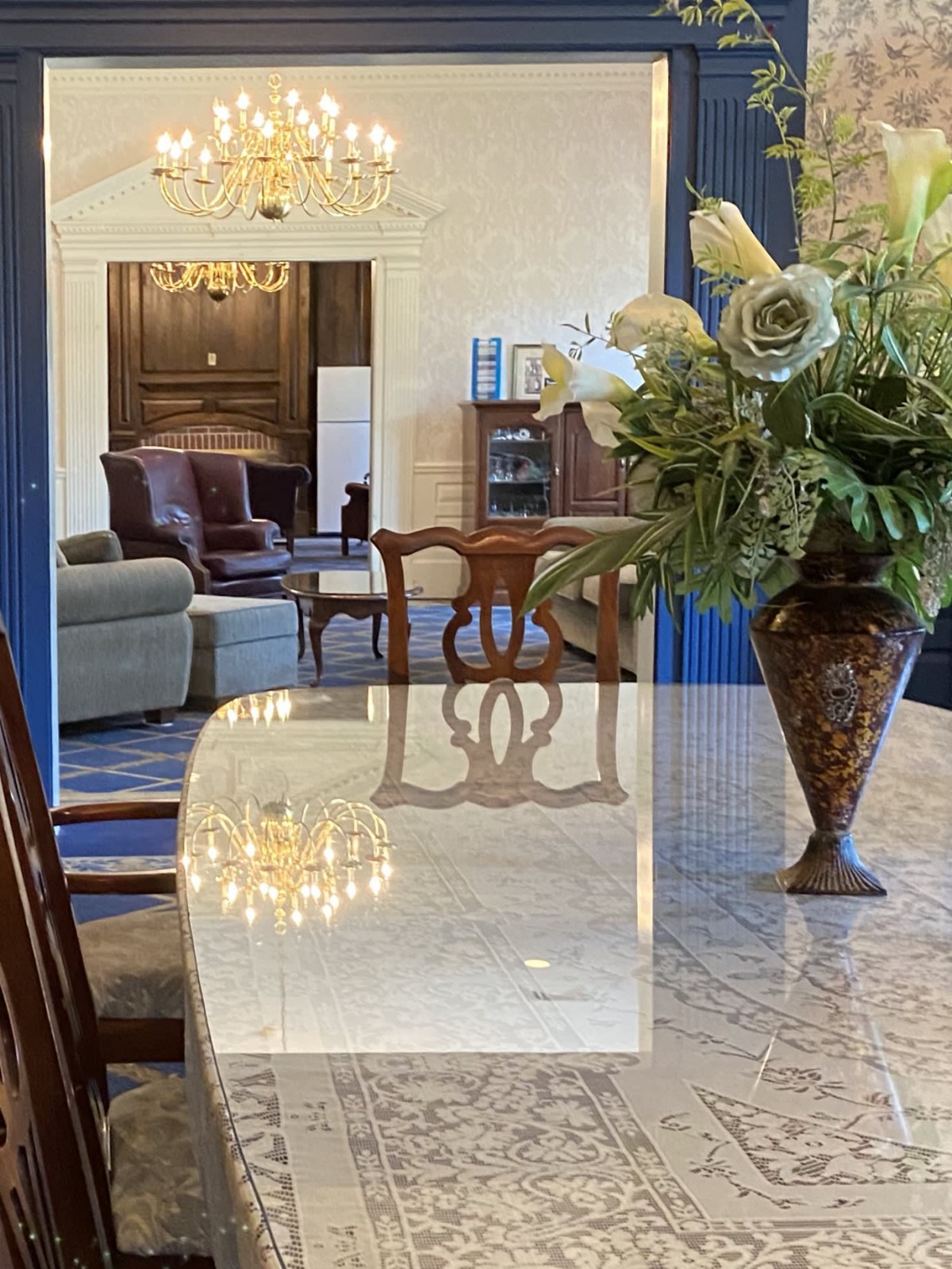 A well-decorated dining area featuring a marble table with an elegant flower arrangement, adjacent to a cozy living room.