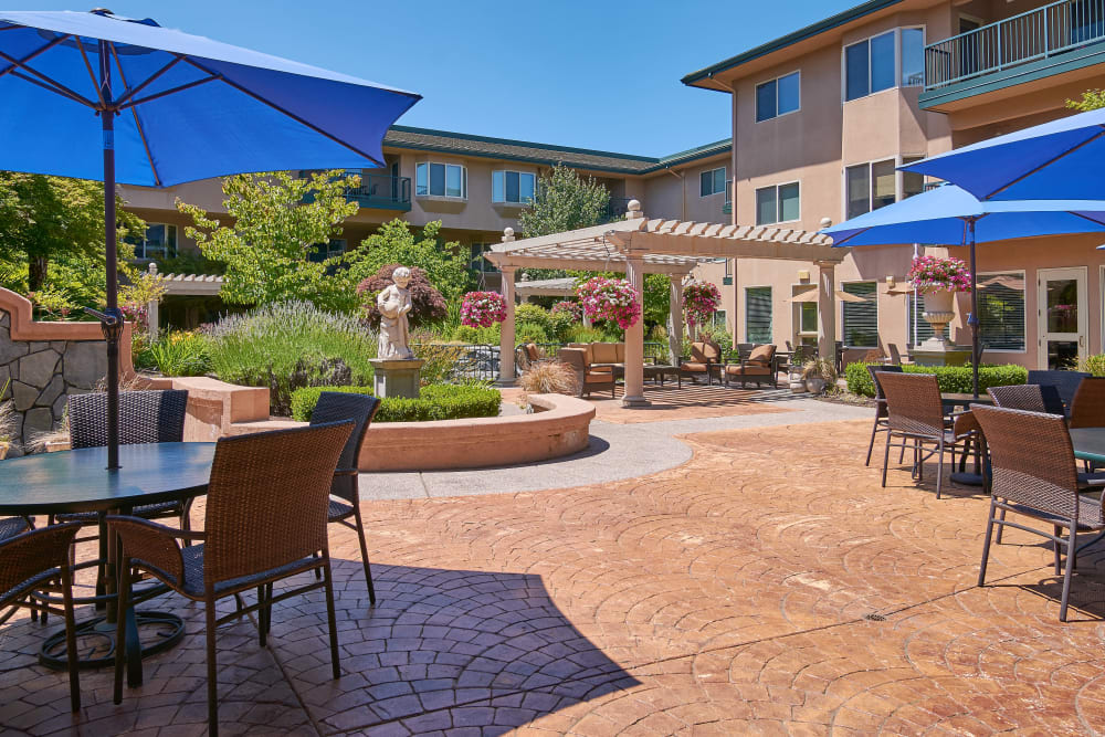 A sunny courtyard with outdoor seating and umbrellas in an apartment complex.