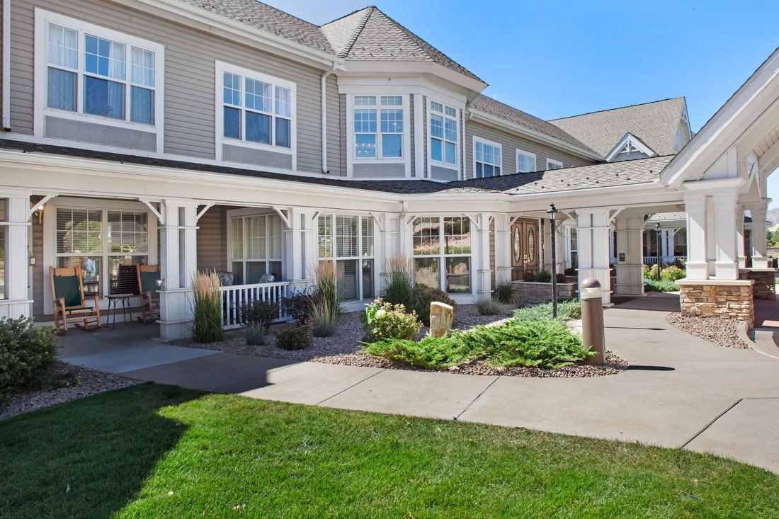 A two-story residential building with a porch and well-maintained garden.