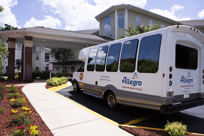 A shuttle bus parked in front of a hotel entrance on a sunny day.