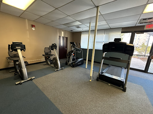 A view of a small indoor gym featuring various exercise equipment including treadmills and ellipticals.