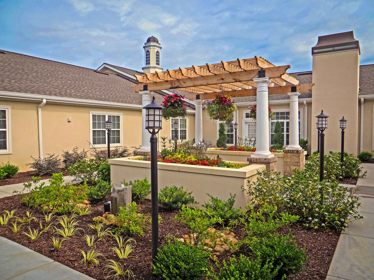 A beautifully landscaped garden with a pergola and well-maintained outdoor space in front of a residential building.