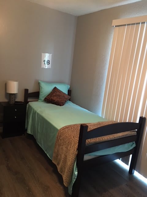 A small, minimalist bedroom with a single bed and a nightstand.