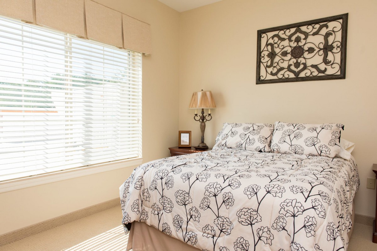 A cozy bedroom with floral bedding and a large window letting in natural light.