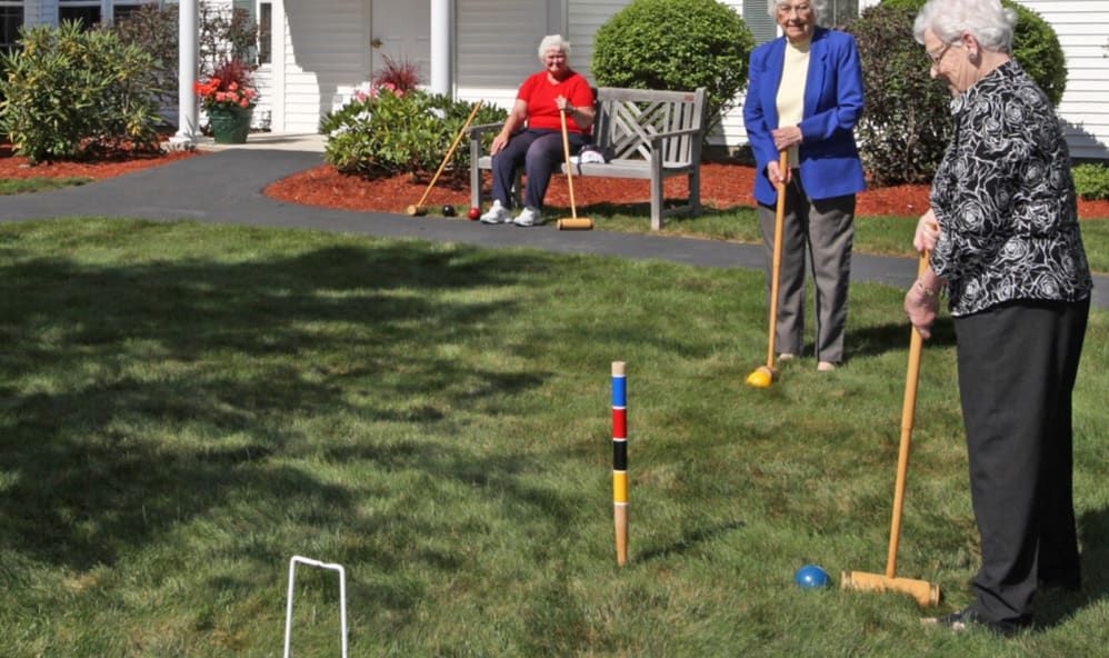 Elderly individuals enjoying a game of croquet outdoors.
