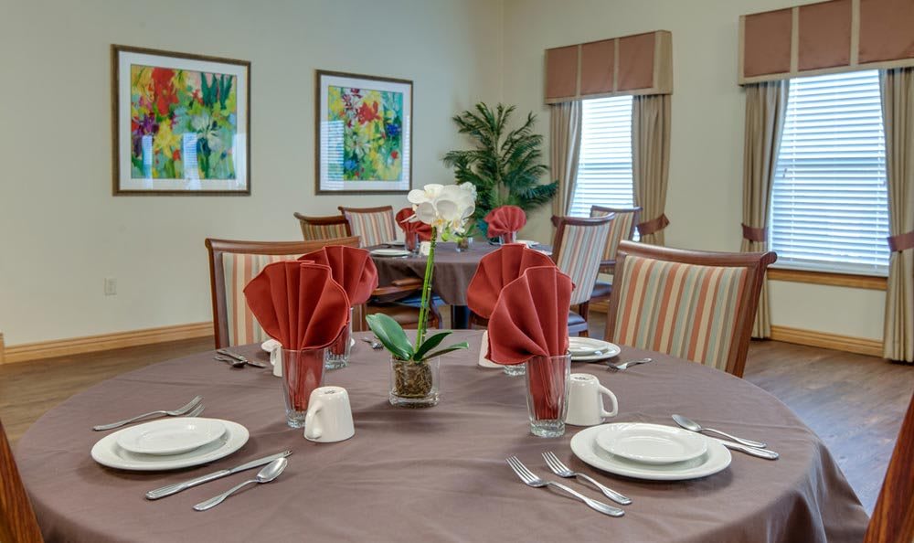 A neatly arranged dining table with red folded napkins and white dishware in an elegantly decorated room.
