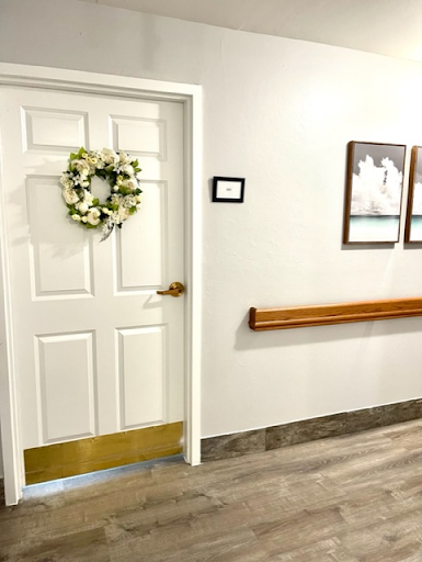 A beautifully decorated door adorned with a wreath, leading into an inviting hallway with framed pictures.