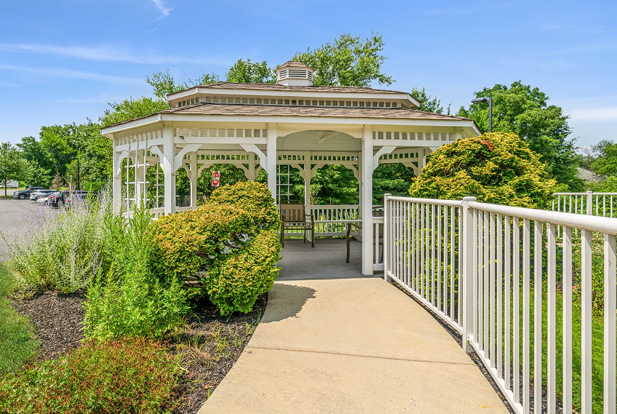 A charming gazebo surrounded by lush greenery and a smooth pathway.