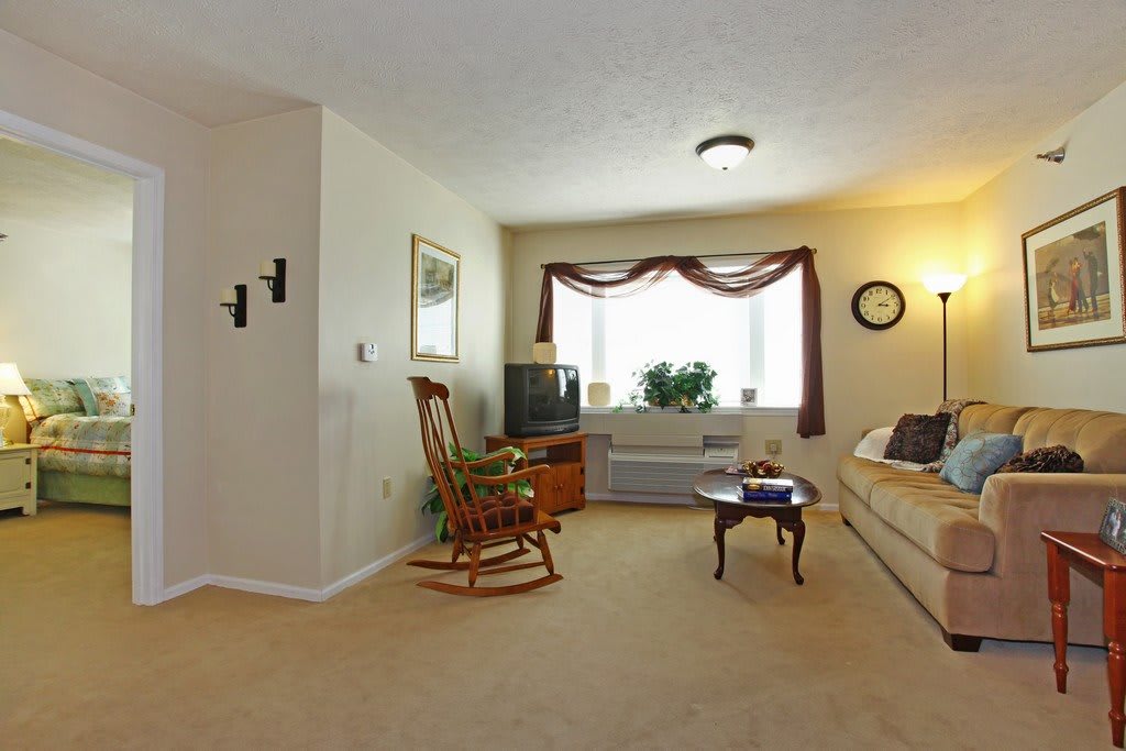 A cozy living room with a sofa, rocking chair, and a television set near the window.