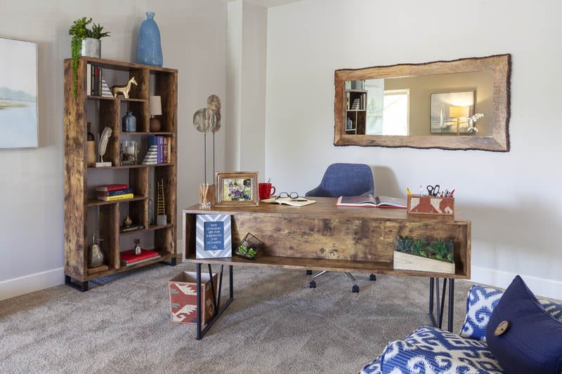 A stylish home office with a wooden desk and a bookshelf, featuring modern decor elements.