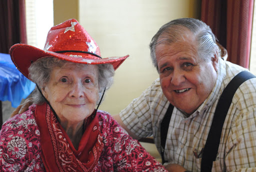 A joyful elderly couple enjoying a moment together, dressed in vibrant red attire and hats.