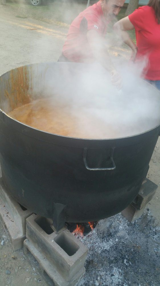 A large pot emits steam while cooking outdoors.