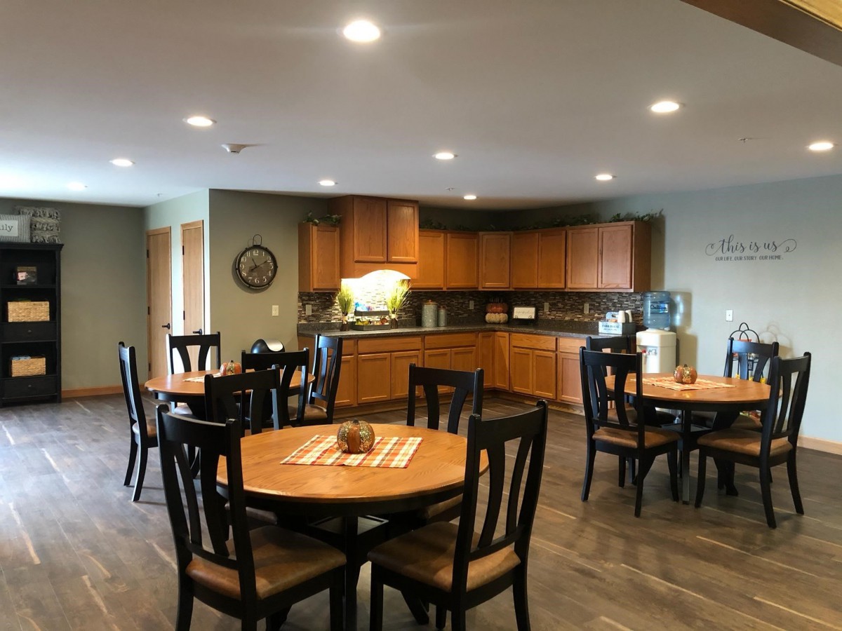 A cozy dining area with wooden tables and chairs adjacent to a kitchen.
