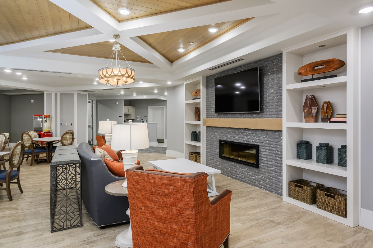 A modern living room with orange chairs, a fireplace, and built-in shelves.