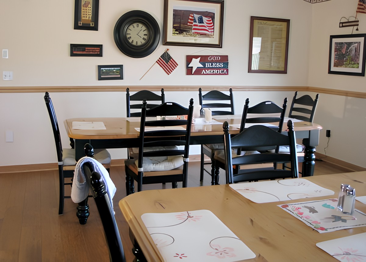 A cozy dining area in a restaurant with wooden tables and chairs, featuring American-themed decorations.