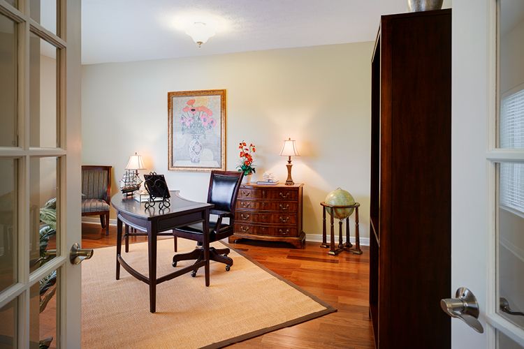 A well-organized home office with wooden furniture and warm lighting.