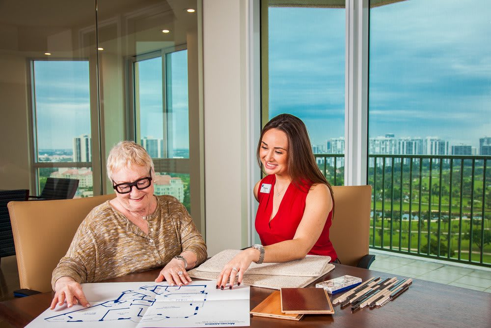 Two women discussing architectural plans in an office with a view.
