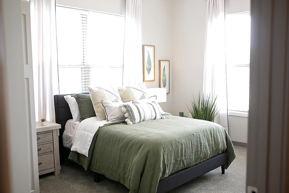 A cozy bedroom with green bedding and stylish decor.
