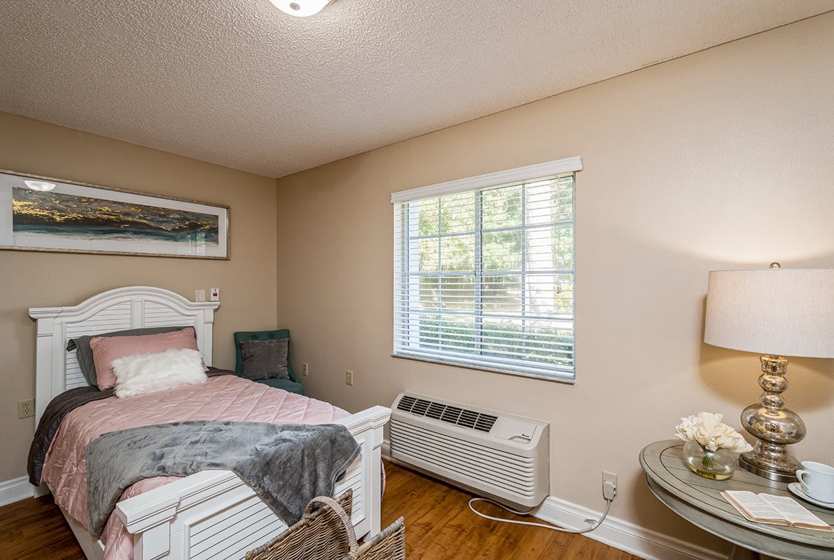 A cozy bedroom with a bed, window, and air conditioning unit.