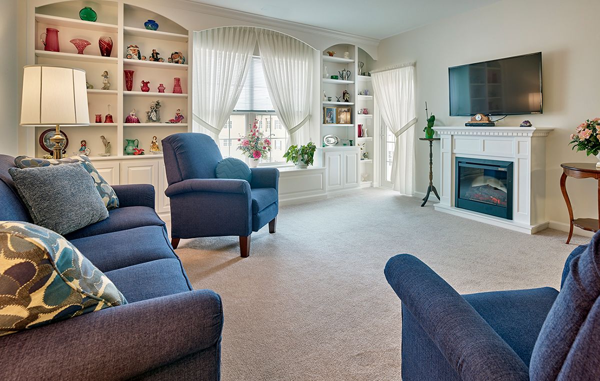 A cozy living room with blue furniture and decorative bookshelves.