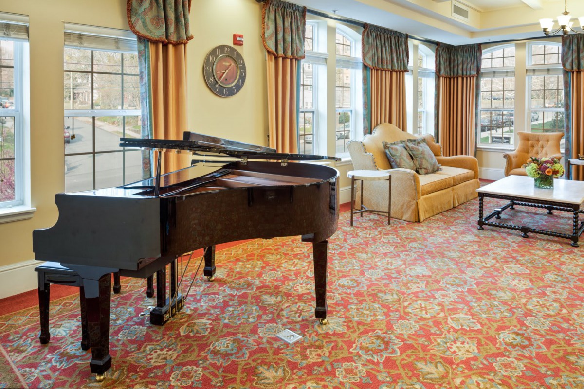 A cozy living room with a grand piano and comfortable seating.