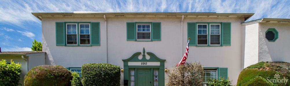 A two-story building with green shutters and an American flag displayed outside.