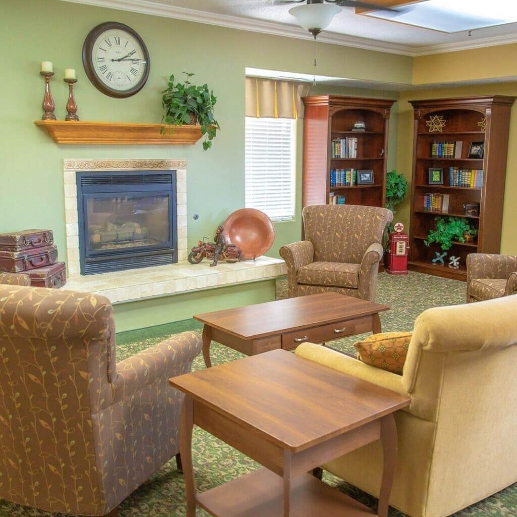 A cozy living room with comfortable chairs, a fireplace, and a bookshelf.