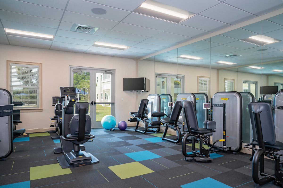 A modern gym with various exercise machines and colorful flooring.