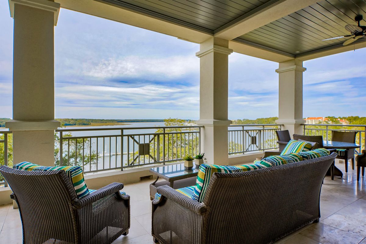 A serene balcony with comfortable seating overlooking a beautiful water view.