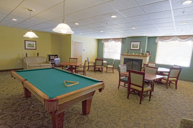 A cozy recreational room featuring a billiard table and a seating area by the fireplace.