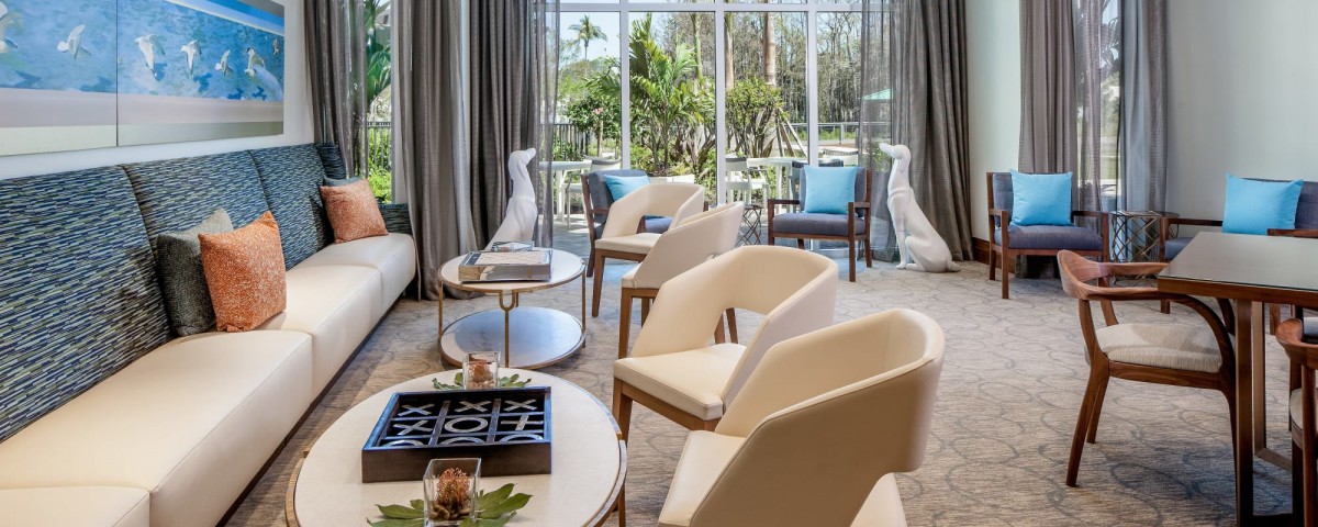 A modern living room with neutral-colored chairs, decorative elements, and large windows allowing natural light.