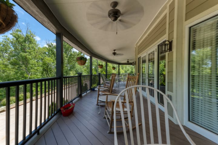 A cozy porch with rocking chairs and ceiling fans overlooking a lush garden.