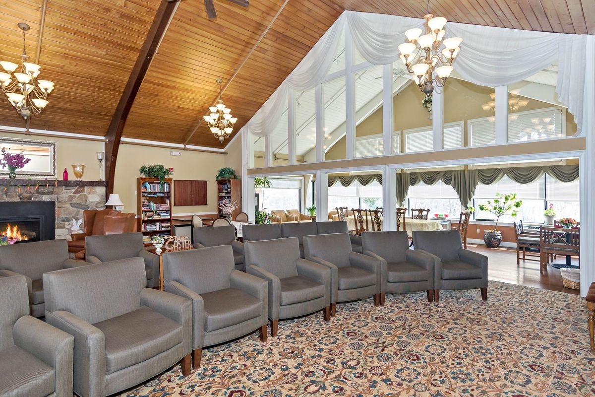 A spacious lounge area with a row of comfortable chairs, high wooden ceilings, and large windows letting in natural light.