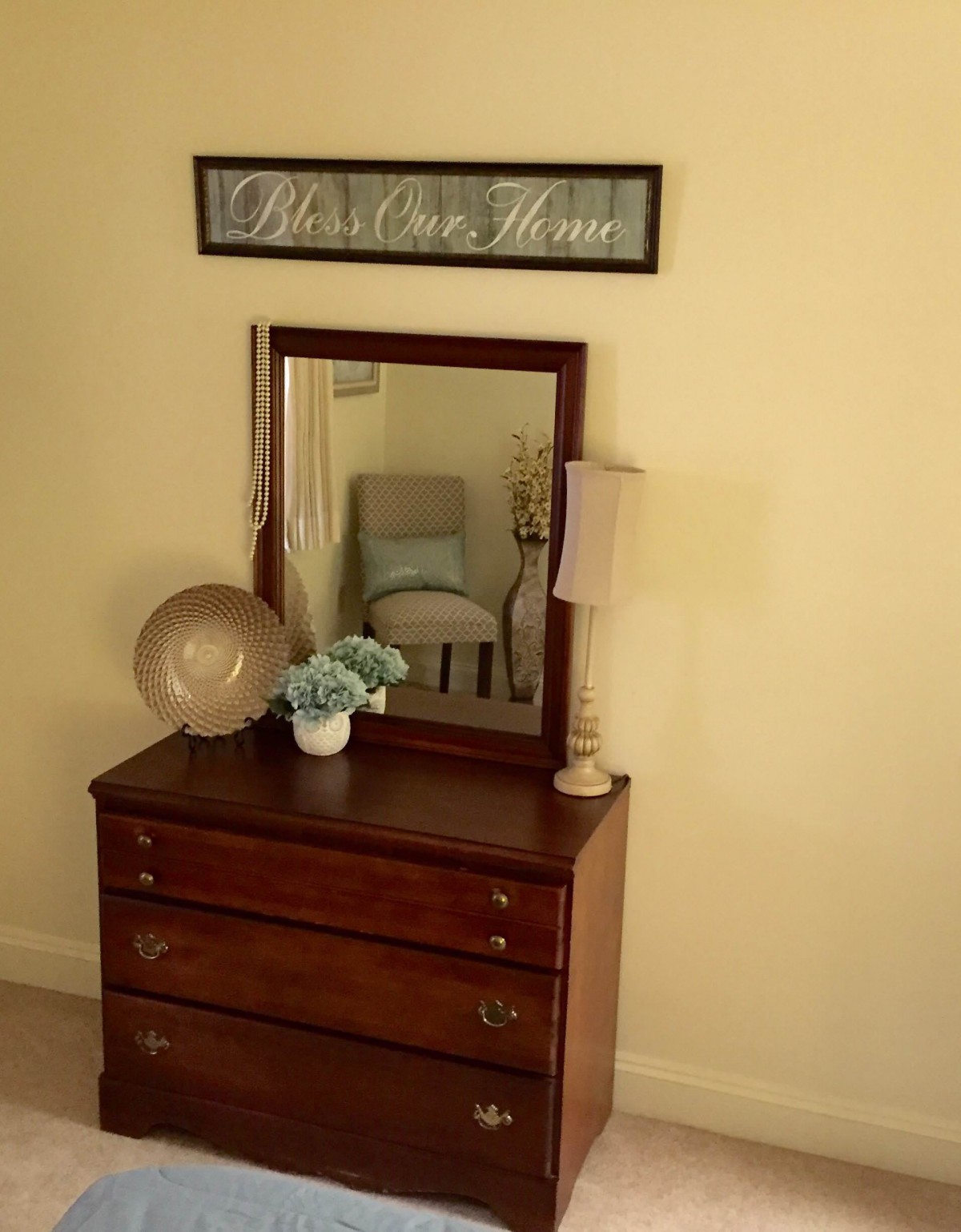 A stylish dresser with a mirror, adorned with decor items and a lamp.