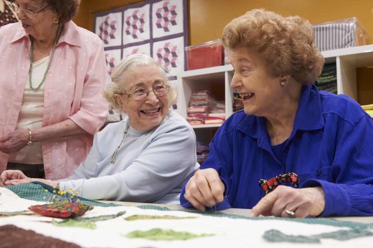 Elderly women enjoying a crafting session together, sharing laughter and conversation.