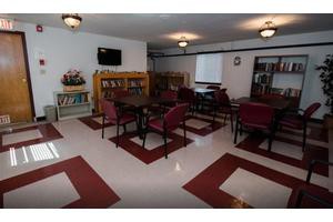 A cozy library reading room with tables, chairs, and bookshelves.