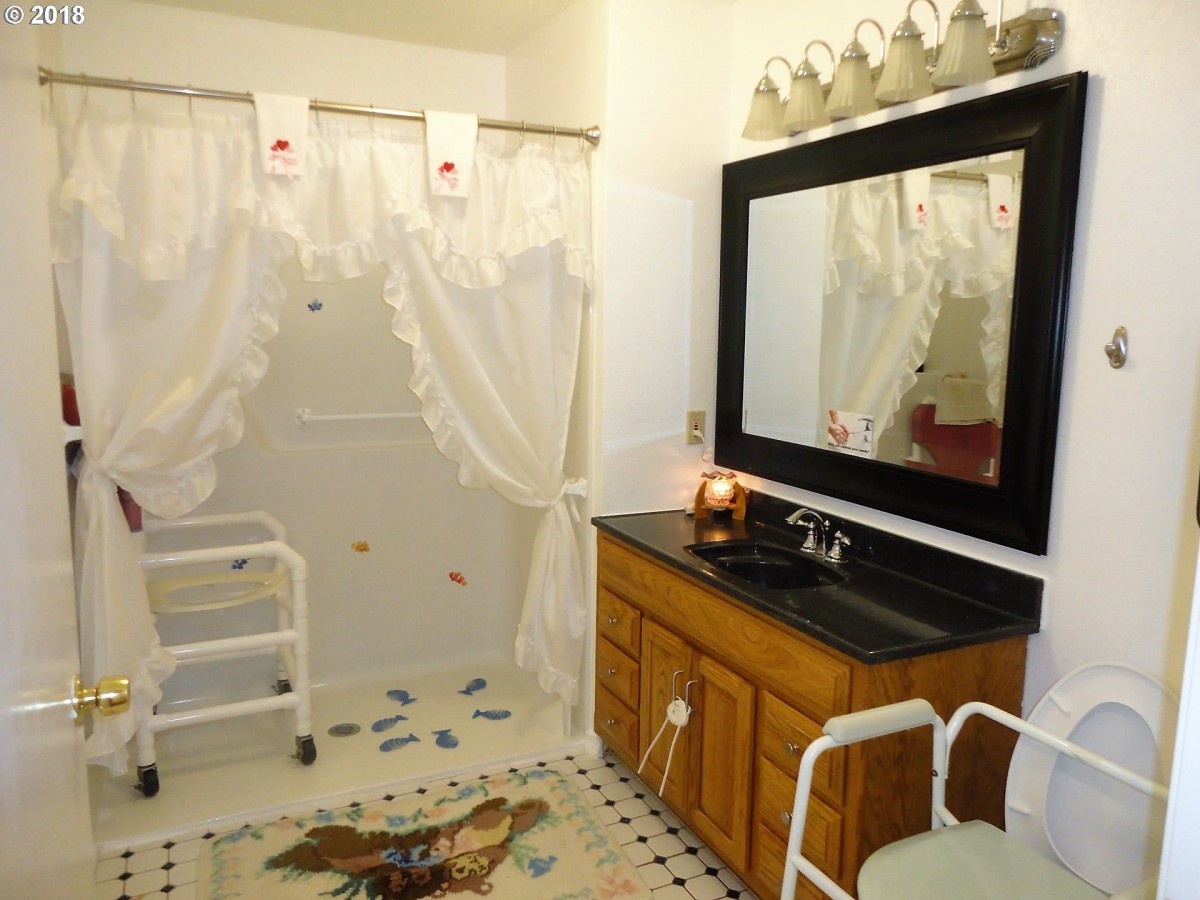 An accessible bathroom with a vanity and shower area, complete with decorative curtains and a mirror.