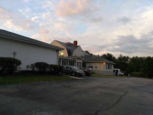 A peaceful residential scene during the evening, showcasing houses and parked cars under a cloudy sky.