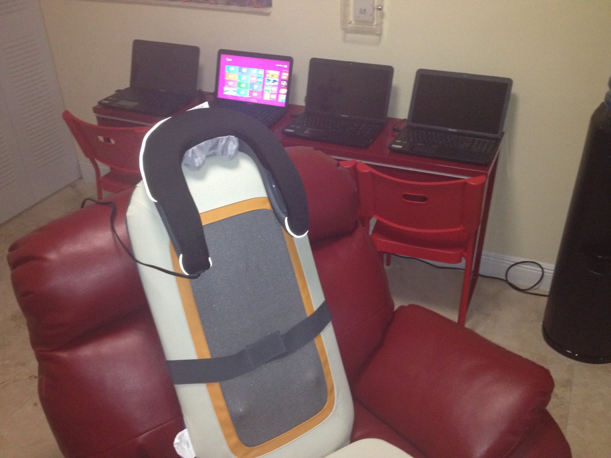 An office space with four laptops and a massage chair.