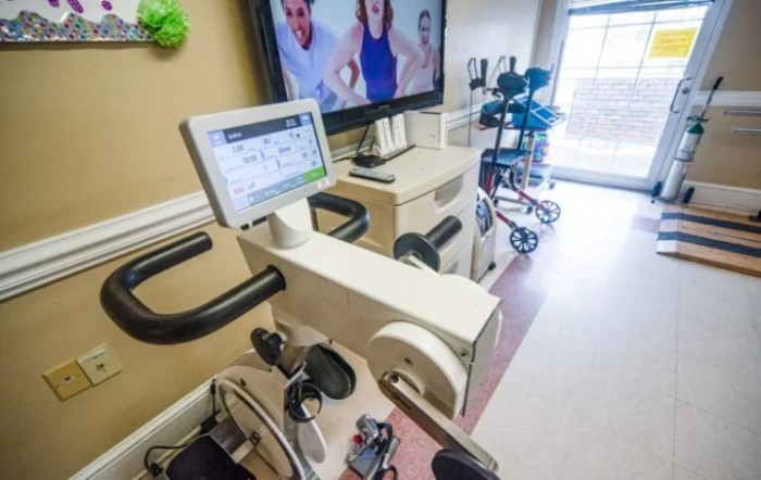 A rehabilitation room equipped with stationary exercise bikes and a monitor for virtual fitness sessions.