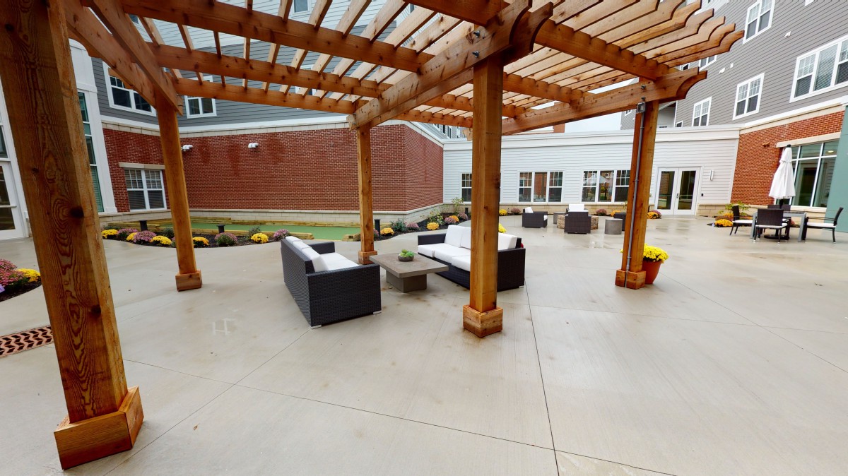 An outdoor patio featuring a wooden pergola with comfortable seating.