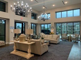 A spacious living room with elegant chandeliers, large windows, and comfortable sofas.