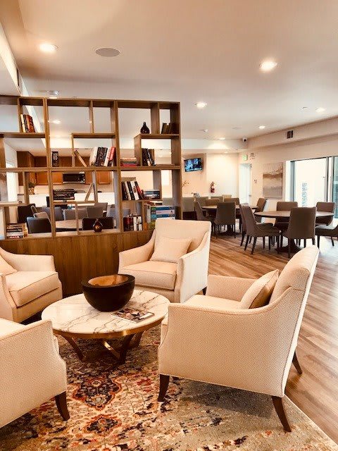 A modern and cozy living room featuring a comfortable seating area with armchairs, a round coffee table, and stylish shelving.