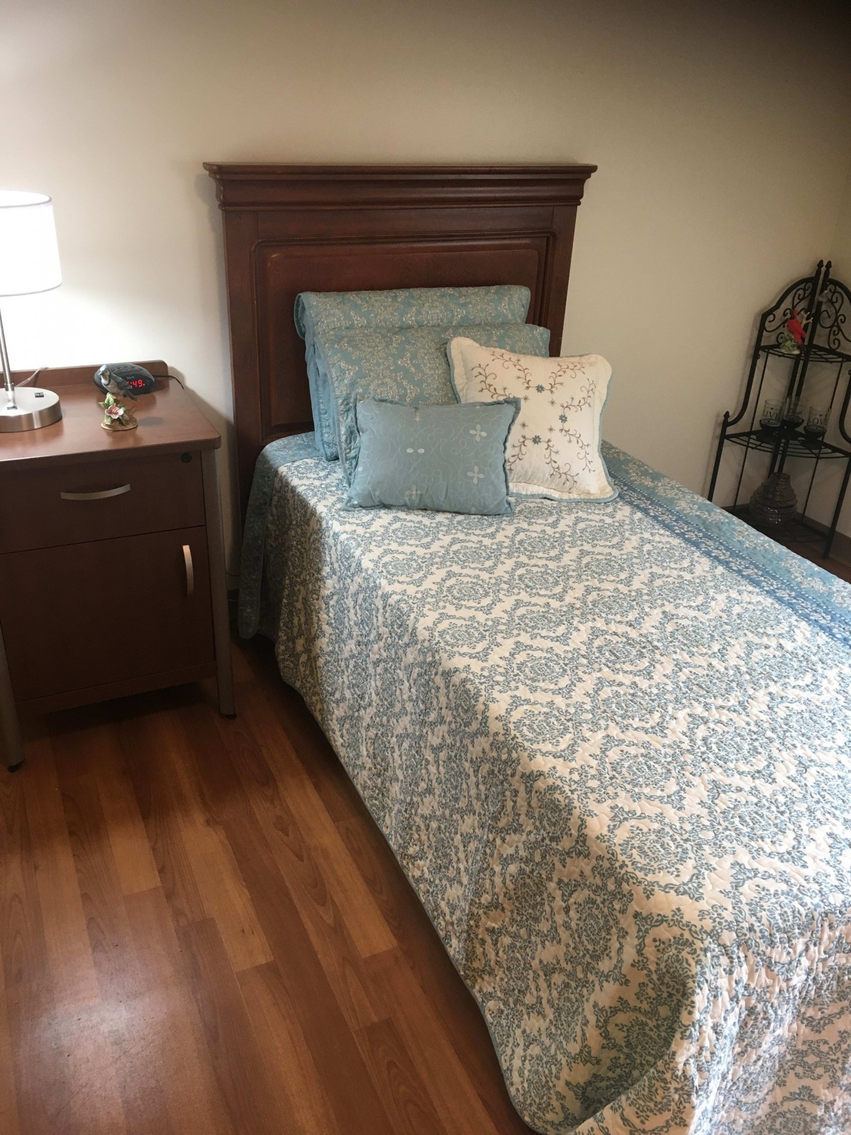 A neatly made bed with patterned bedding next to a nightstand and lamp.