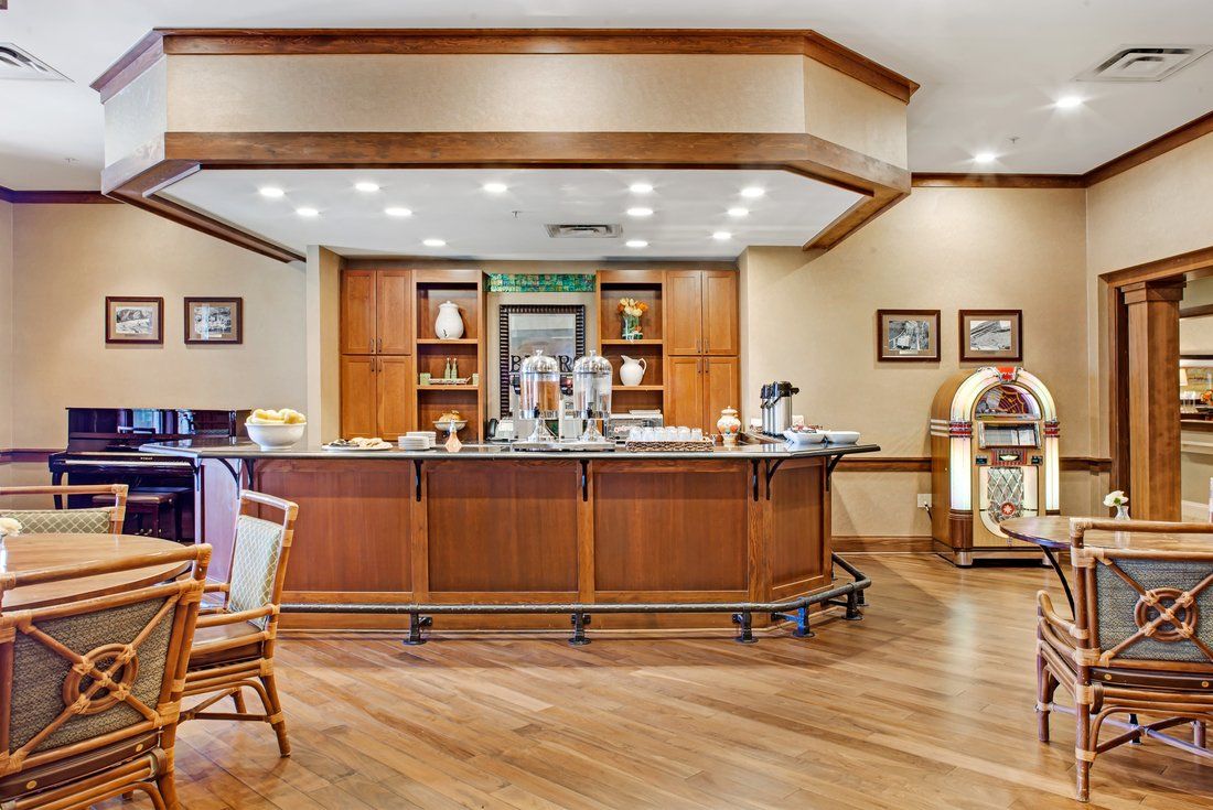 A cozy bar area with a wooden counter and seating, featuring warm lighting and a jukebox.